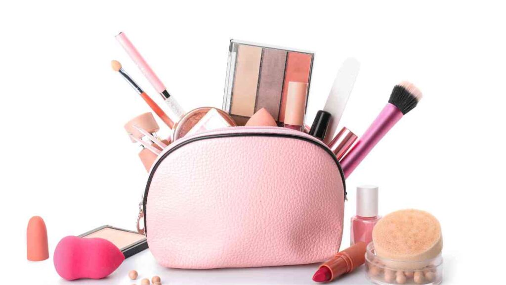 pink cosmetic bag with makeup products on a white background