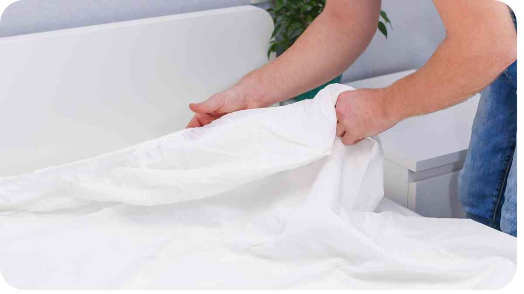 a person putting a sheet on a bed